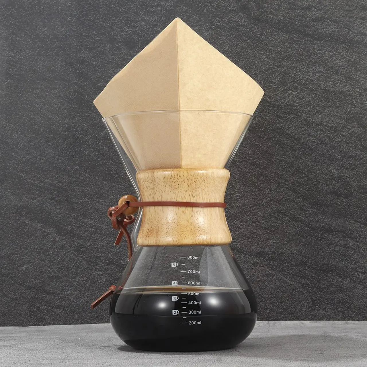A natural-brown square coffee filter folded in a glass carafe.
