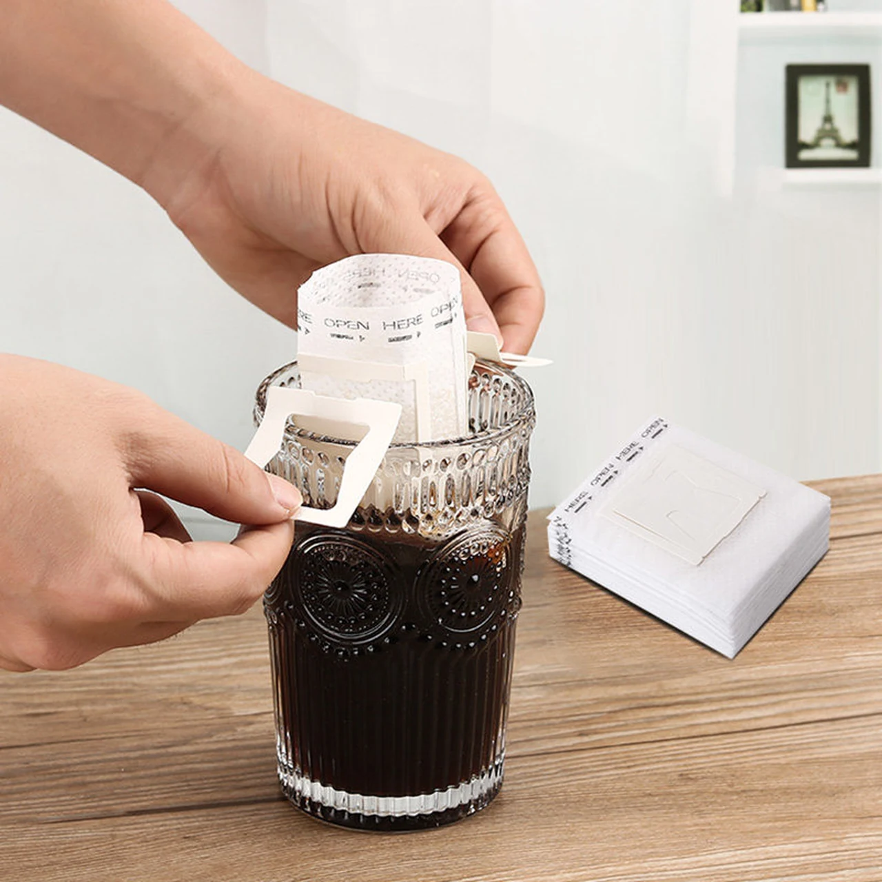 Hands opening the supports of a drip filter bag.